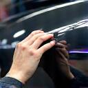 एक मैकेनिक एक कार के पेंट फिनिश का निरीक्षण कर रहा है